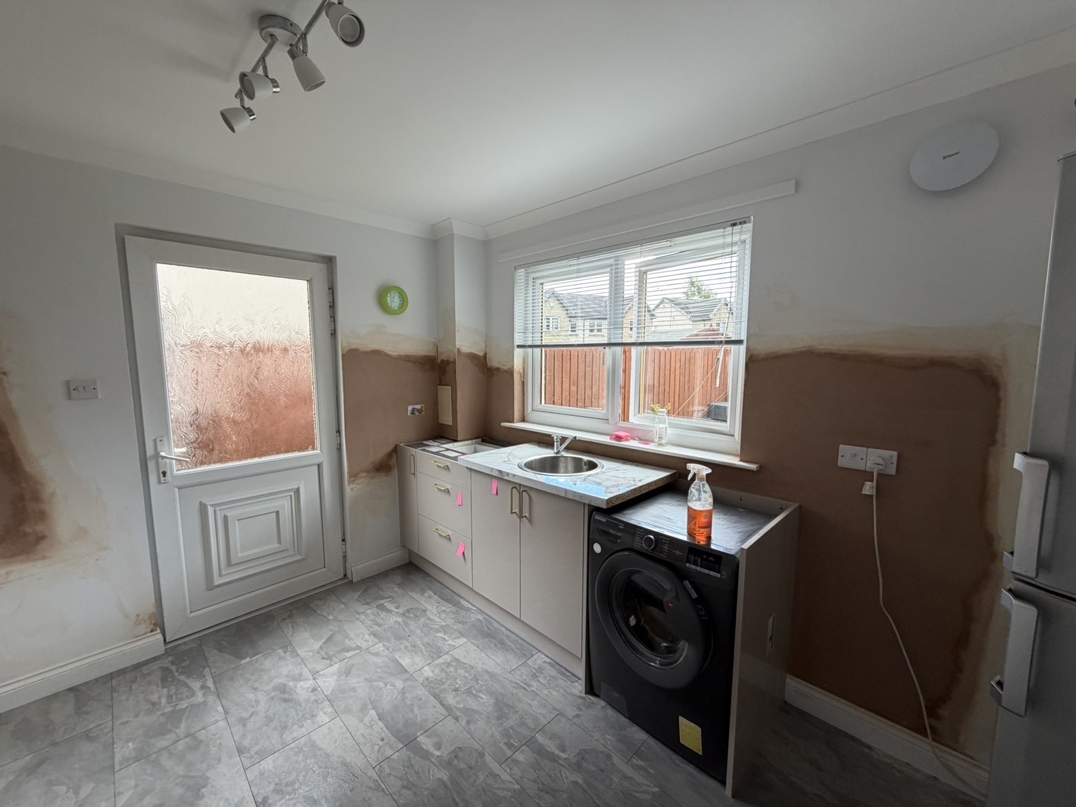 Kitchen walls re-skimmed around units and window — neat clean finish